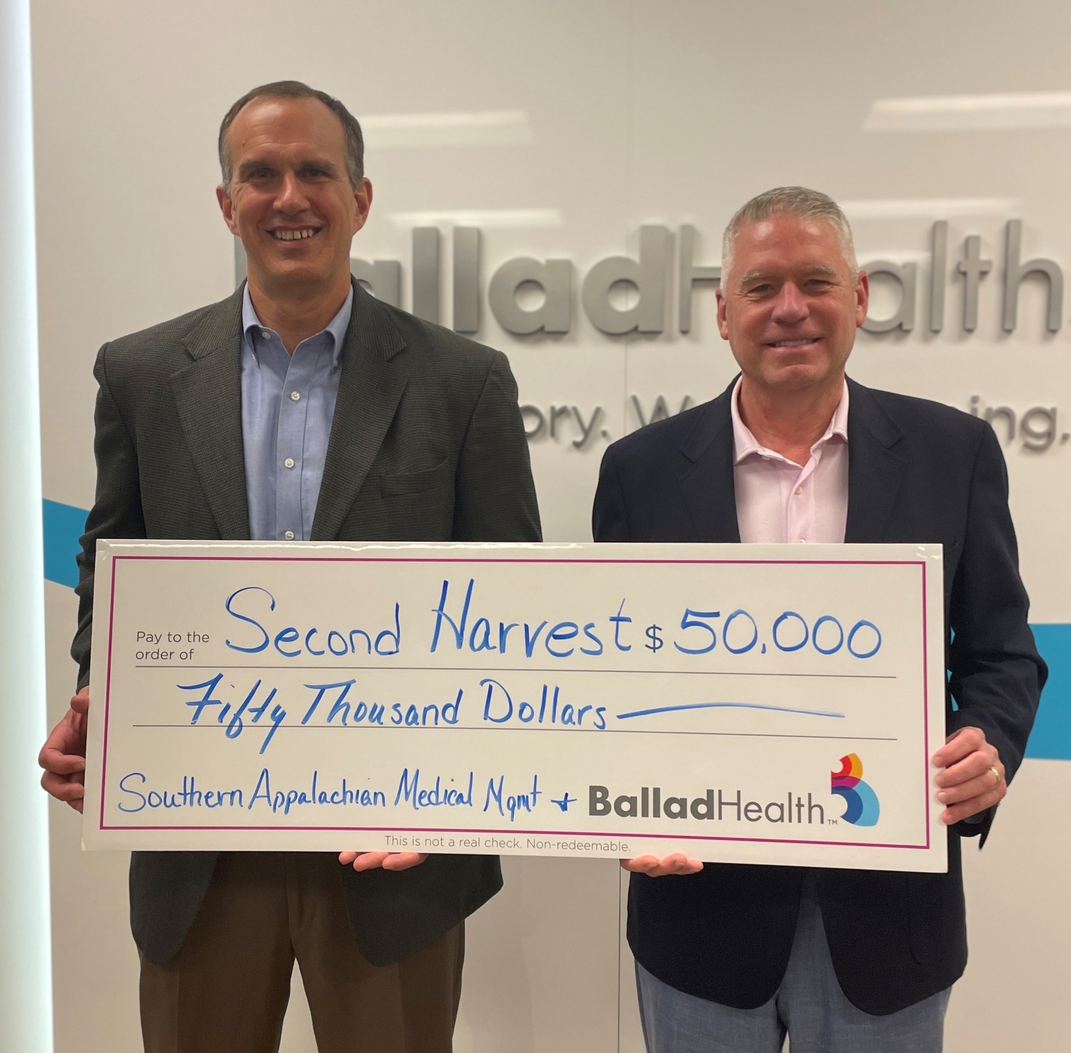 T. Lisle Whitman, MD, with Appalachian Orthopedics, and Eric Deaton, chief operating officer of Ballad Health holding a giant presentation check for $50,000