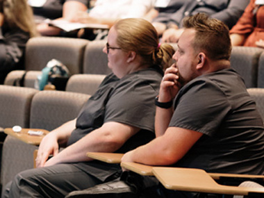 Two Ballad Health team members listening to a lecture in an auditorium