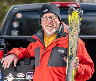 Dickie Hill holding skis and leaning on his truck