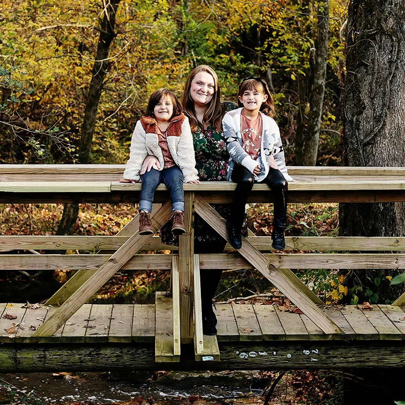 Strong Futures Alumni, Blake, with her children on a creek bridge in Northeast Tennessee